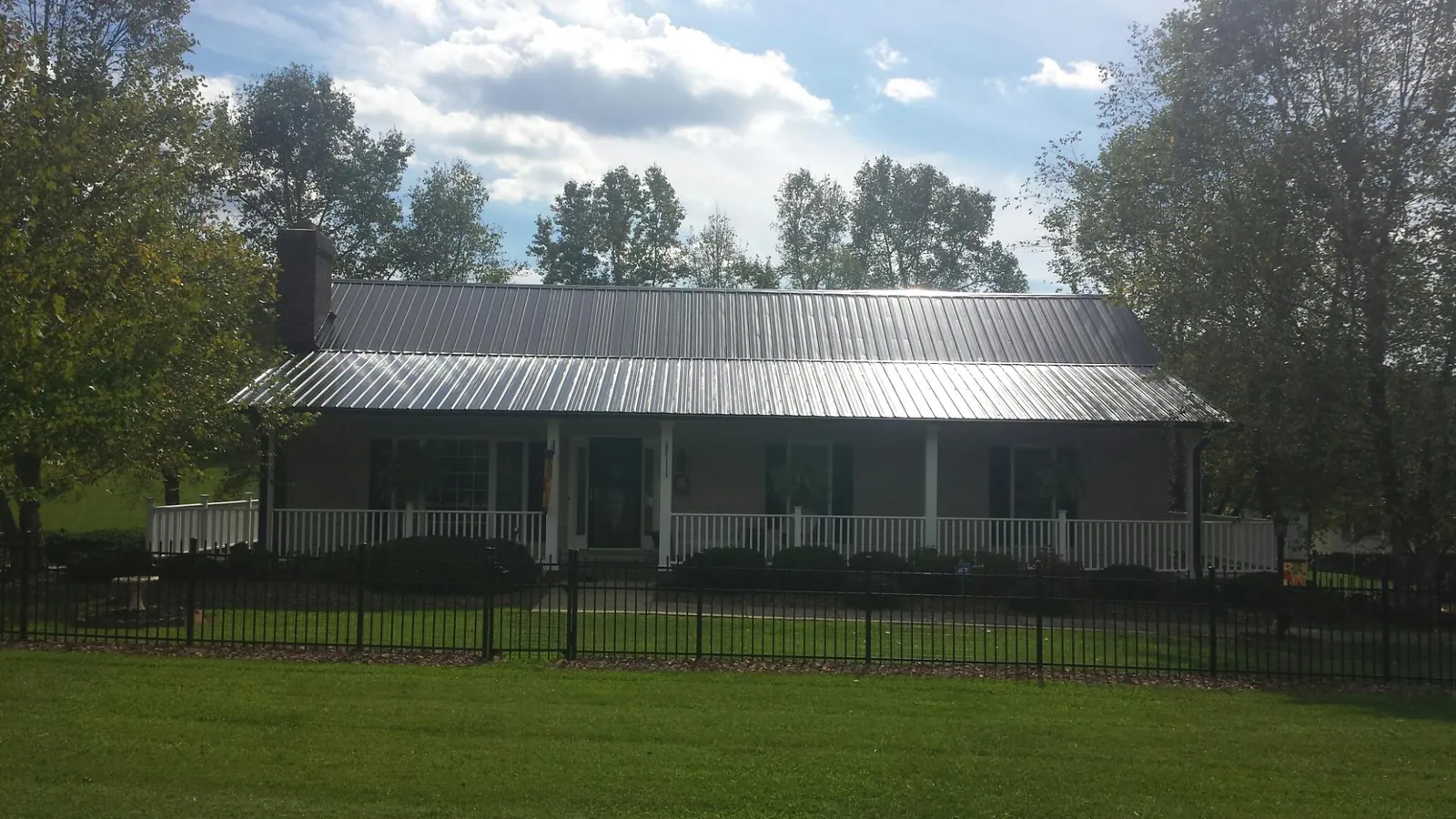 Gray metal roof on a brick ranch with a full width front porch — Gutter Guard Installation work by our crew in Lake Placid